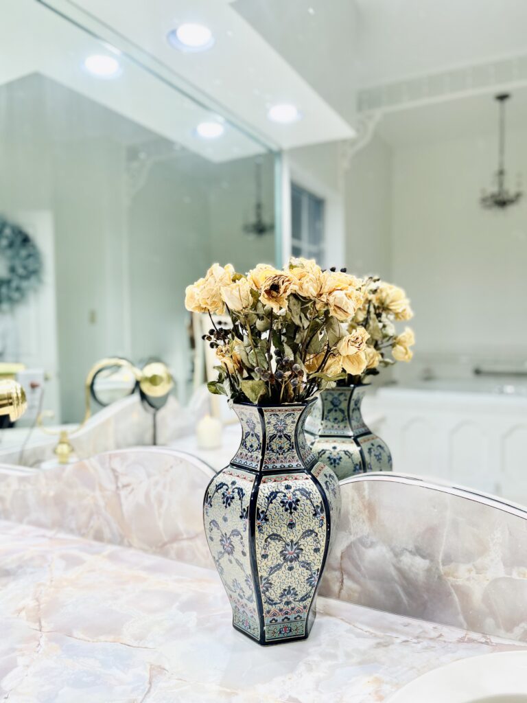a beautiful serene bathroom scene with dry white roses in a colorful blue vase
