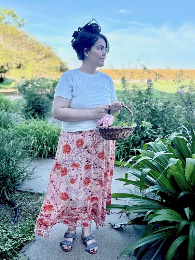 A young woman looking off into the distance holding a basket full of  Belinda roses