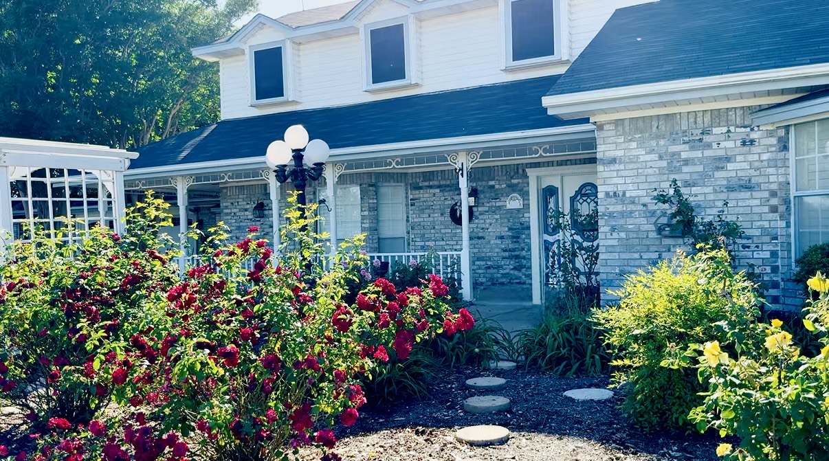 a beautiful vintage home with gorgeous roses and a simple yet welcoming stepping stone path