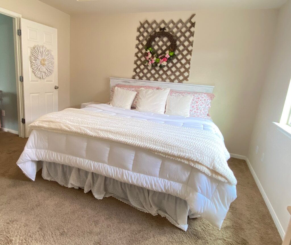 a beautiful white and pink master bedroom massive king size bed with a lot of cozy pillows