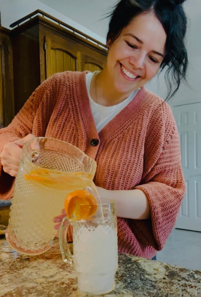 a young woman pouring lemonade, smiling in gratitude 