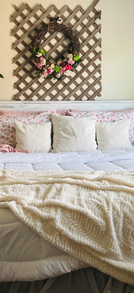 an up close image of a beautiful bedroom in cozy white, pinks and gentle florals with a lattice for a wall hanging
